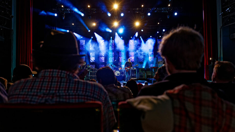 Back of two seated audience members as they watch Jason Isbell play guitar at The Center Theater in Jackson, Wyoming