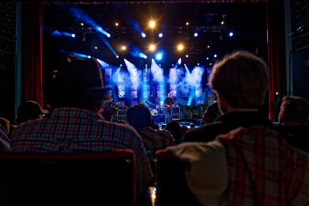 Back of two seated audience members as they watch Jason Isbell play guitar at The Center Theater in Jackson, Wyoming