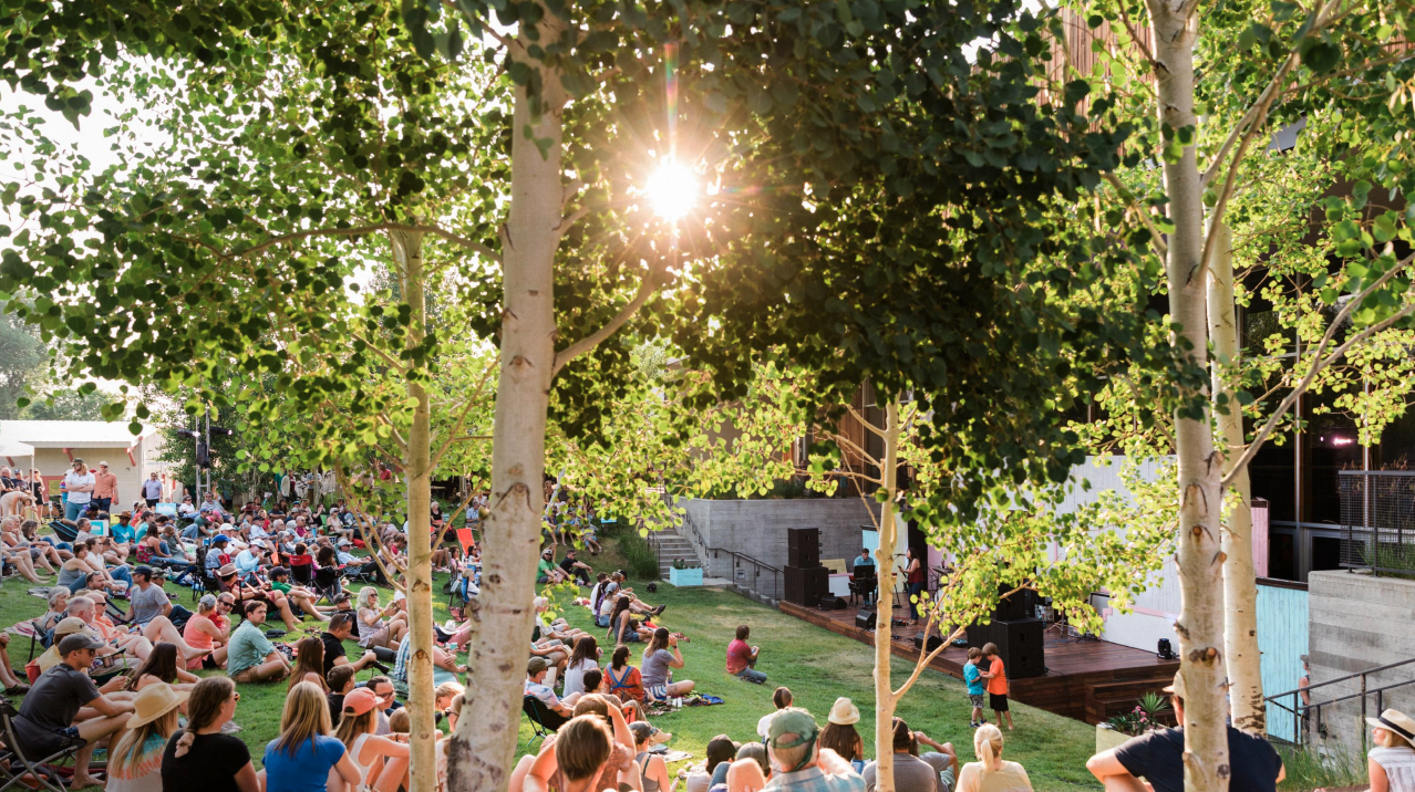 Crowd enjoying outdoor concert on grass in the sunshine at the Center Amphitheater in Jackson, Wyoming
