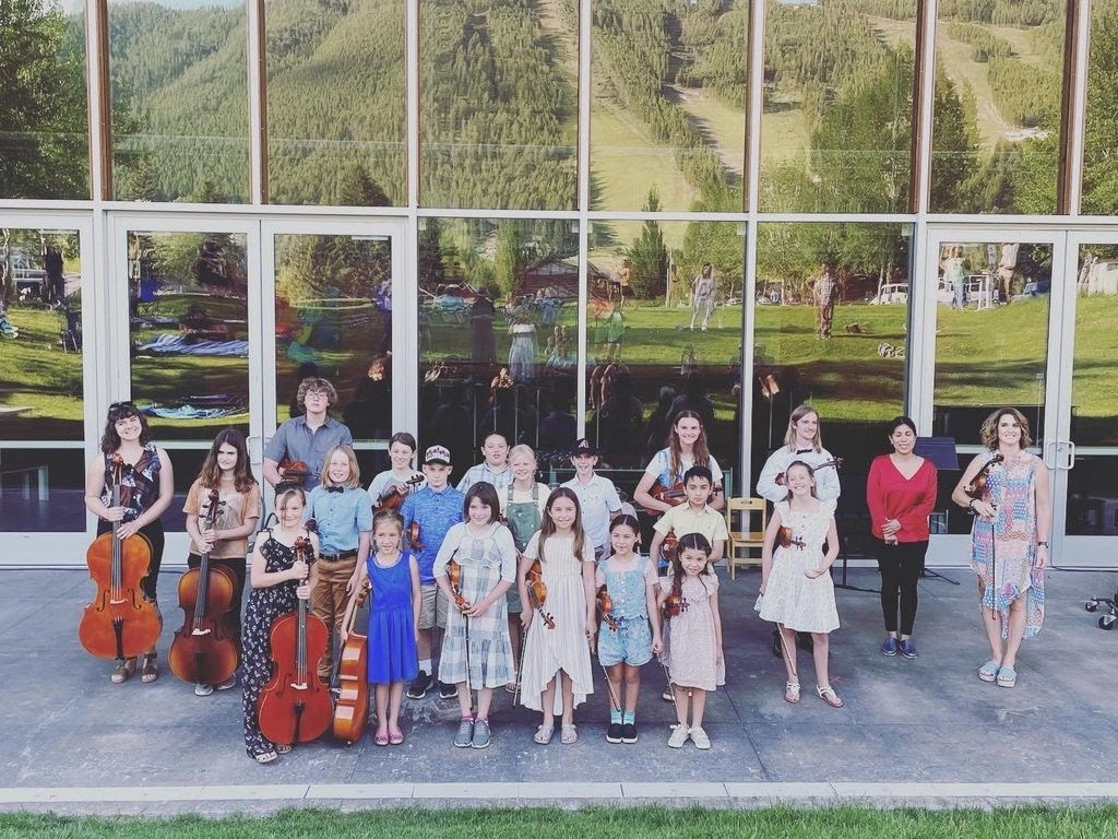 A group of children outside JH Center with instruments partaking in the resident summer class