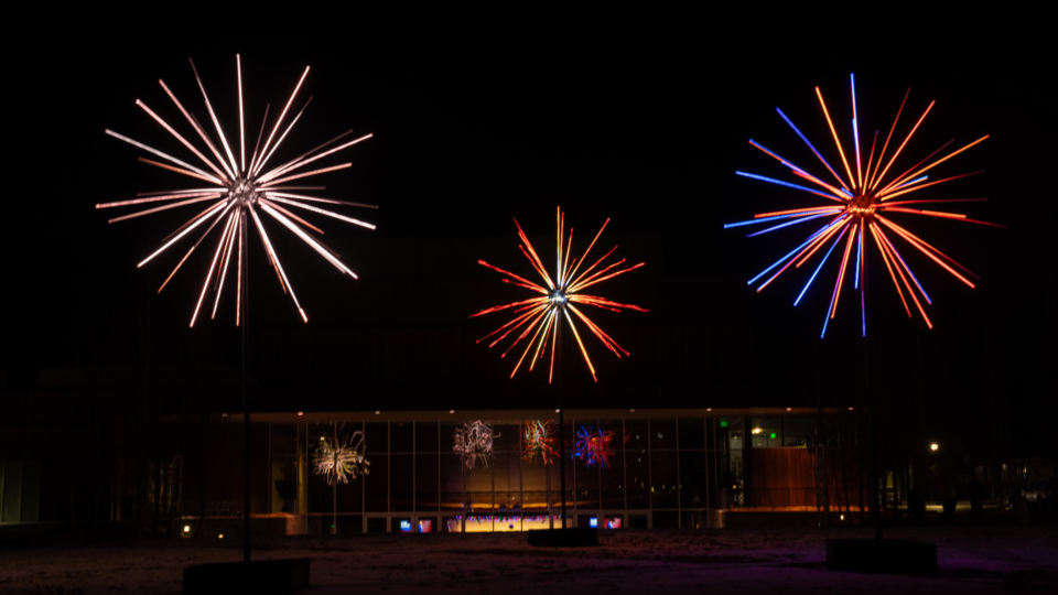 Three colourful glowing art installations that look like fireworks or dandelions