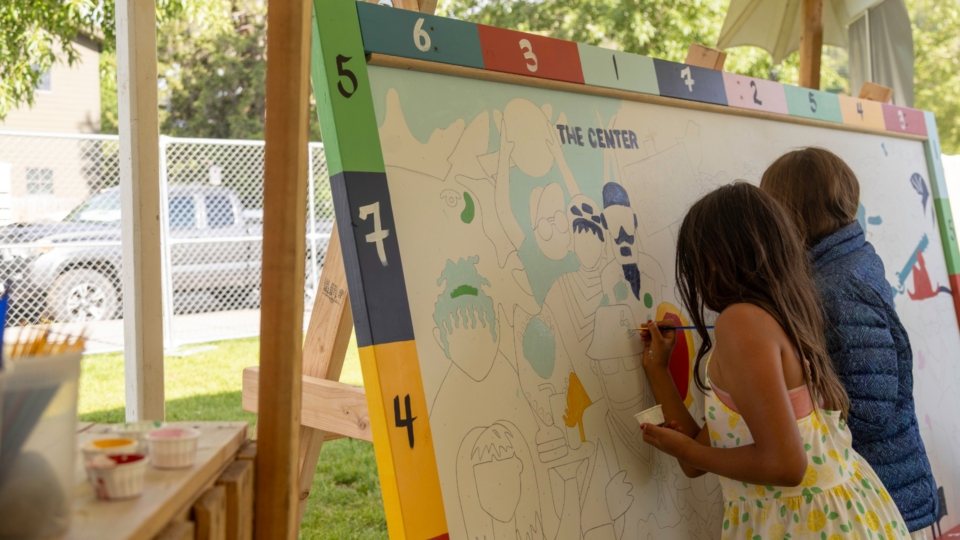 Two children painting a mural outside at the Center for the Arts in Jackson Hole, Wyoming