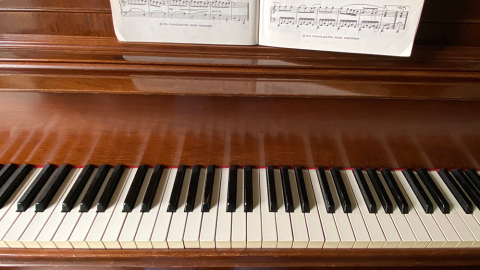 Keys of a brown wooden piano with sheet notation for Jackson Hole music lessons at Center for the Arts