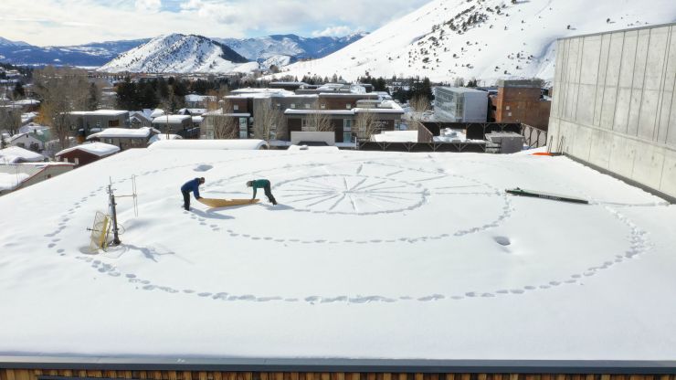 Two people drawing circles and patterns in the snow