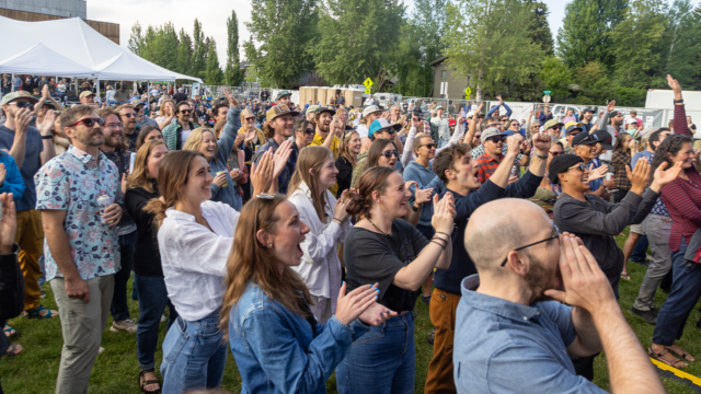 A crowd of people cheering and clapping at the annual Center Benefit Concert for Jackson Hole donations in The Center Park