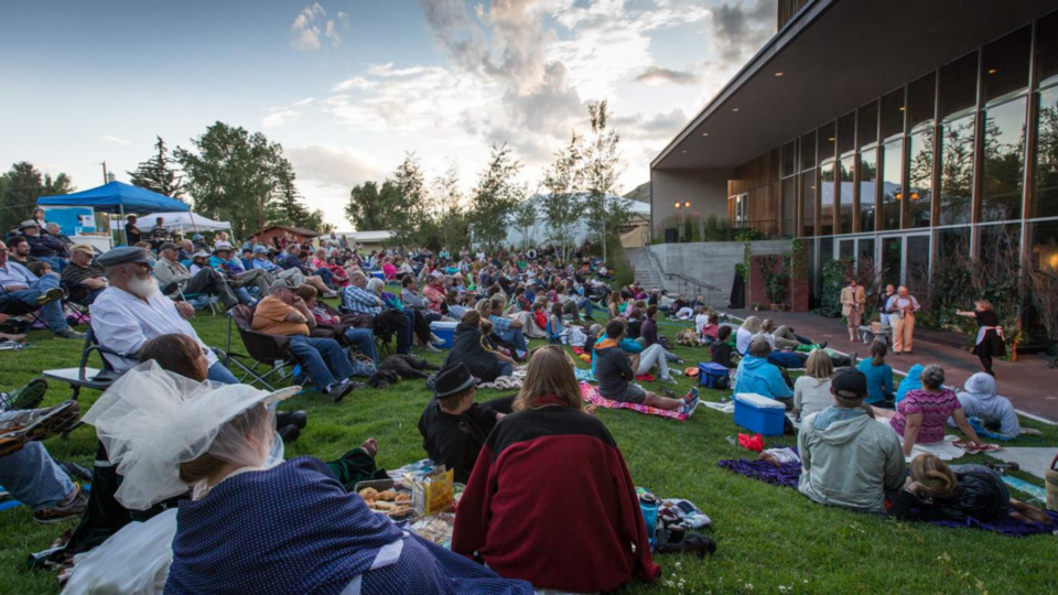 Audience on grass watching Thin Air Shakespeare theatre performance outdoors at the Center Amphitheater in Jackson, Wyoming